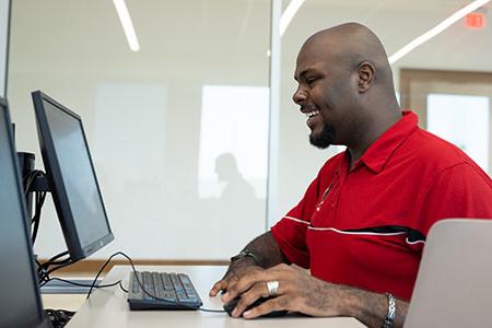 一位男学生坐在电脑前浏览奖学金 